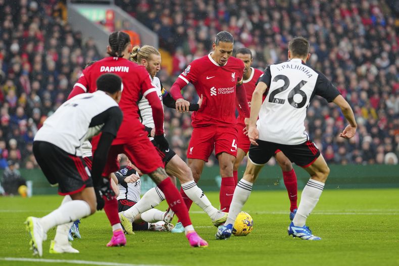 Virgil van Dijk del Liverpool disputa el balón con Tim Ream del Fulham (centro a la izquierda), durante el partido de la Liga Inglesa entre el Liverpool y el Fulham jugado en el estadio de Anfield, en Liverpool, Inglaterra, el domingo 3 de diciembre de 2023. (AP Foto/Jon Super)