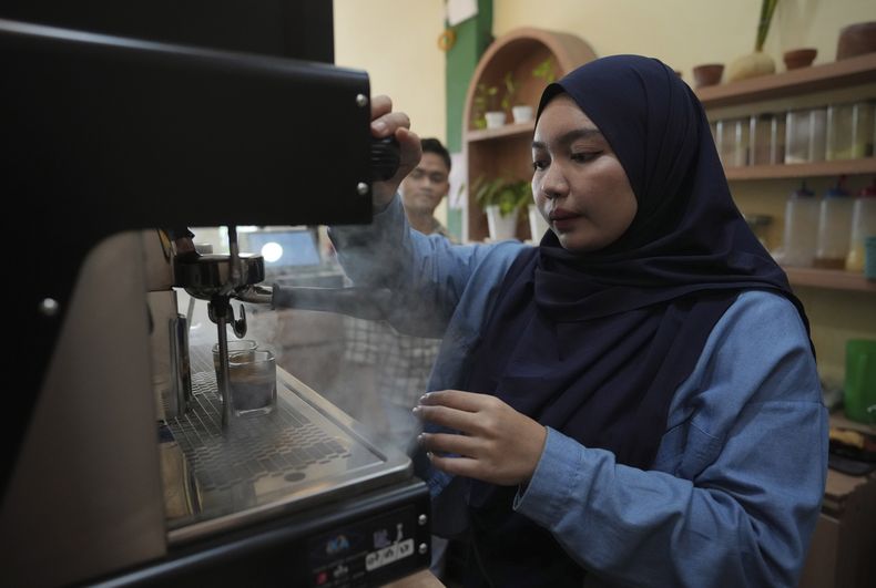 Qurrata Ayuni, una superviviente del tsunami de 28 años, acciona una máquina de café en la cafetería que gestiona en Banda Aceh, Indonesia, el miércoles 11 de diciembre de 2024. (AP foto/Achmad Ibrahim)