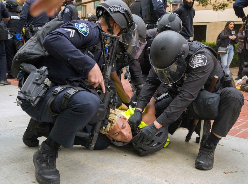 ARCHIVO - La policía tira al suelo a un manifestante pro-palestino para atarle las muñecas en la Universidad de California, Irvine, después de que la policía comenzara a desplazar a los manifestantes y un campamento fuera del patio, el 15 de mayo de 2024, en Irvine, California (Leonard Ortiz/The Orange County Register via AP, Archivo)