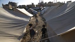 Niños palestinos desplazados por los bombardeos israelíes sobre Gaza caminan entre tiendas proporcionadas por la ONU en un campamento levantado en Khan Younis, el 19 de octubre de 2023. (AP Foto/Fatima Shbair)