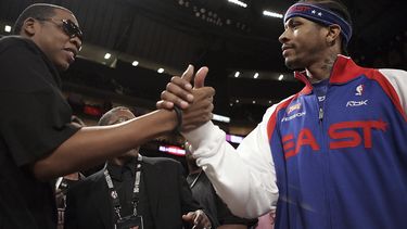 ARCHIVO - El rapero Jay-Z, a la izquierda, le da la mano a Allen Iverson, del NBA All-Star Philadelphia 76ers, antes del inicio del partido de baloncesto NBA All-Star en Houston, el 19 de febrero de 2006. Así como la banda sonora de una película ayuda a los espectadores a seguir la acción de la narración a través de cada giro de la trama, el hip hop ha hecho lo mismo con el basquetbol través de la NBA. (Foto AP/LM Otero, archivo)