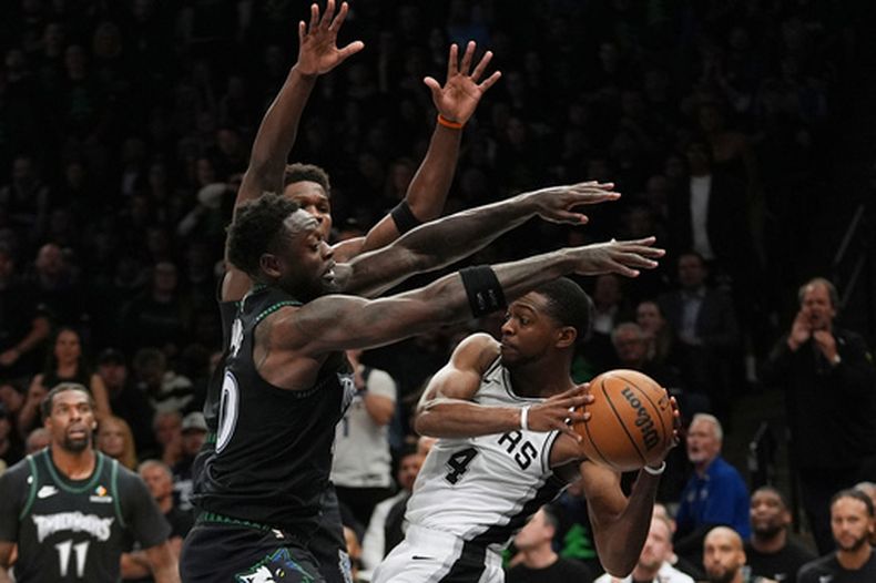 Deaaron Fox (4), de los Spurs de San Antonio, es presionado por Julius Randle, izquierda, y Anthony Edwards, centro, durante la segunda mitad del cuarto juego de la serie de segunda ronda de los playoffs del baloncesto de la NBA, el domingo 10 de mayo de 2026, en Minneapolis. (AP Foto/Abbie Parr)