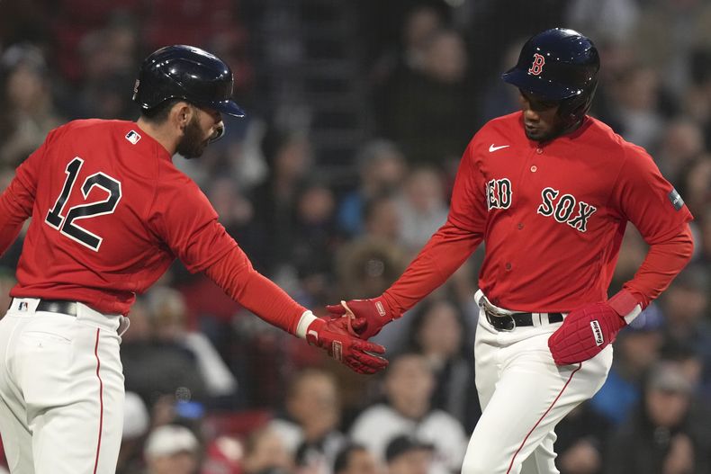 Pablo Reyes, derecha, de Medias Rojas de Boston, es felicitado en el plato por Connor Wong (12) después de que Reyes anotara carrera con un sencillo de Jarren Duran en contra de los Marineros de Seattle durante la segunda entrada del juego de béisbol, el miércoles 17 de mayo de 2023, en Boston. (AP Foto/Steven Senne)