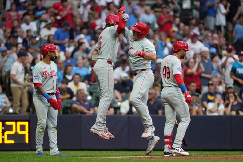 J.T. Realmuto, centro derecha, de los Filis de Filadelfia, celebra con Bryson Stott después de batear un jonrón de tres carreras durante la sexta entrada del juego de béisbol de Grandes Ligas contra los Cerveceros de Milwaukee, el sábado 13 de junio de 2026, en Milwaukee. (AP Foto/Aaron Gash)