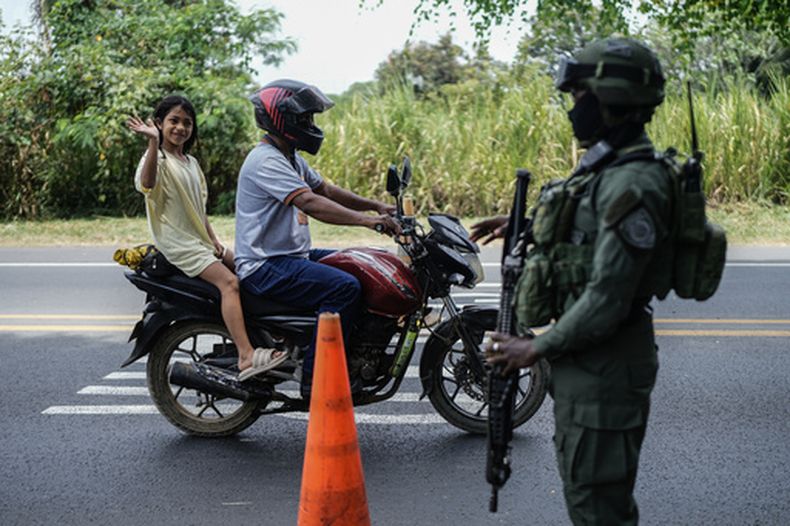 Una niña saluda con la mano al pasar por un control de seguridad antes de la toma de posesión del presidente electo Abelardo de la Espriella en Jamundí, a las afueras de Cali (Colombia), el jueves 6 de agosto de 2026. (Foto AP/Iván Valencia)