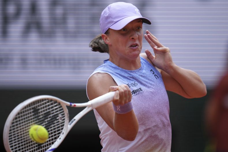 Iga Swiatek devuelve ante Emma Raducanu durante la segunda ronda del Abierto de Francia, el miércoles 28 de mayo de 2025, en París. (AP Foto/Christophe Ena)