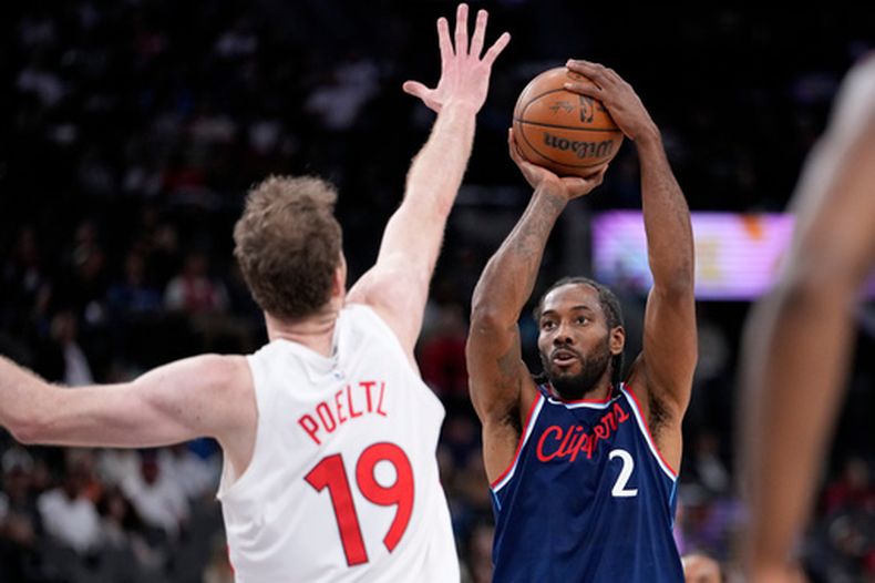 Kawhi Leonard, derecha, de los Clippers de Los Ángeles, dispara sobre Jakob Poeltl, de los Raptors de Toronto, durante la primera mitad del juego de baloncesto de la NBA, el miércoles 25 de marzo de 2026, en Inglewood, California. (AP Foto/Mark J. Terrill)