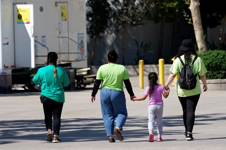 Una niña con empleadas de un refugio para niños migrantes en Pomona, California, el 2 de julio del 2021. (AP foto/Marcio Jose Sanchez, Pool)