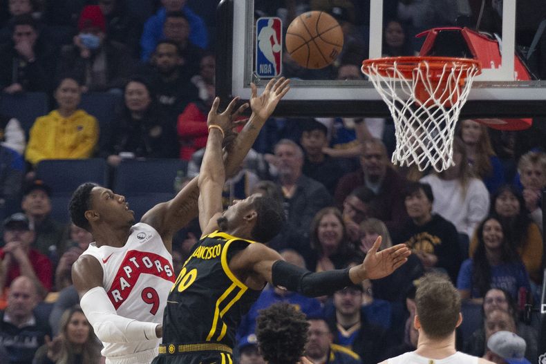 RJ Barrett (9), de los Raptors de Toronto, alista una bandeja sobre el alero Jonathan Kuminga (00), de los Warriors de Golden State, durante el primer cuarto del juego de baloncesto de la NBA, el domingo 7 de enero de 2024, en San Francisco. (AP Foto/D. Ross Cameron)