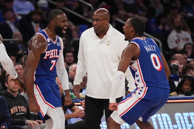 El guardia de los 76ers de Filadelfia, Jaylen Brown, a la izquierda, celebra un enceste de tres puntos con su compañero de equipo, el guardia Tyrese Maxey, a la derecha, mientras observa el entrenador en jefe de los Knicks de Nueva York, Mike Brown, al centro, durante la segunda mitad de un partido de básquetbol de la NBA, el martes 20 de octubre de 2026, en Nueva York. (Foto AP/Frank Franklin II)