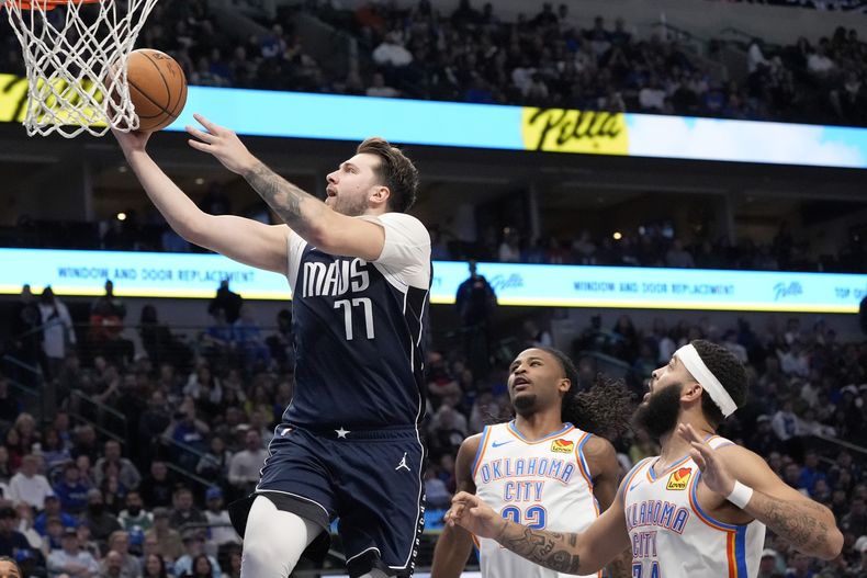 El base de los Mavericks de Dallas Luka Doncic salta a la canasta al superar a Cason Wallace y Kenrich Williams del Thunder de Oklahoma City en el encuentro de la NBA del sábado 10 de febrero del 2024. , right, in the first half of an NBA basketball game in Dallas, Saturday, Feb. 10, 2024. (AP Photo/Tony Gutierrez)