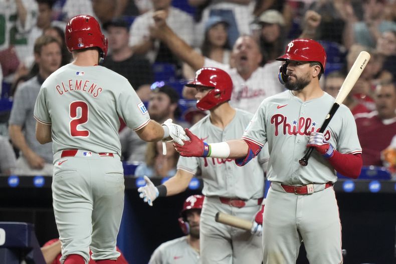 Kody Clemens (2), de los Filis de Filadelfia, se encuentra con Kyle Schwarber, derecha, después de anotar con doblete de Johan Rojas durante la quinta entrada del juego de béisbol en contra de los Marlins de Miami, el viernes 6 de septiembre de 2024, en Miami. (AP Foto/Lynne Sladky)