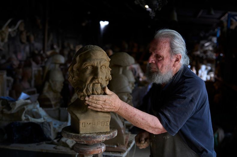 El escultor y ceramista Haralambos Goumas trabaja sobre un busto de terracota del antiguo poeta griego Homero, el autor de la Ilíada y la Odisea, en su taller Aigaleo, un suburbio de Atenas, el miércoles 27 de mayo de 2026. (AP Foto/Petros Giannakouris)