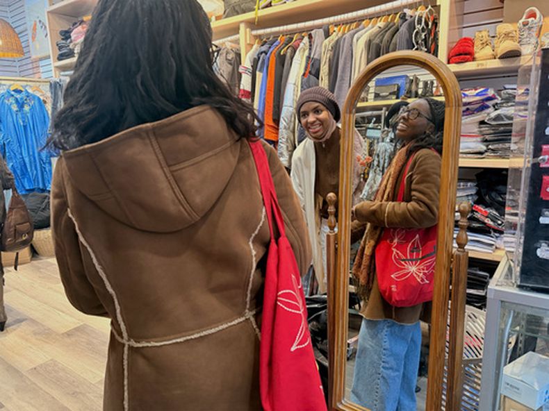 La propietaria Kadjahtou Balde (al centro) interactúa con Tyllah Gorham en la tienda Modify Thrift en el barrio de Harlem, el viernes 23 de enero de 2026, en Manhattan, Nueva York. (Ulaa Kuziez/RNS vía AP)