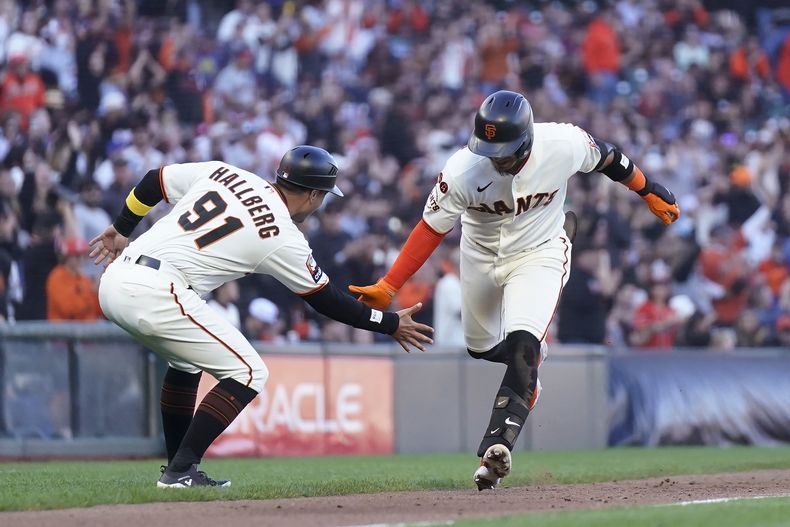 Thairo Estrada, derecha, de los Gigantes de San Francisco, es felicitado por el coach de tercera, Mark Hallberg (91), después de batear cuadrangular en contra de los Rockies de Colorado durante la tercera entrada del juego de béisbol el domingo 10 de septiembre de 2023, en San Francisco. (AP Foto/Jeff Chiu)