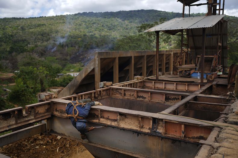 Un trabajador retira placas de hierro en una zona donde se efectúa minería subterránea de oro para reutilizarlas en molinos de piedra en El Callao, estado Bolívar, en Venezuela, el viernes 28 de abril de 2023. (AP Foto/Matias Delacroix)