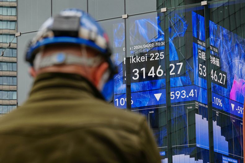 Una persona se encuentra frente a una pantalla electrónica que muestra el índice Nikkei de Japón en una correduría de valores el jueves 2 de abril de 2026, en Tokio. (AP Foto/Eugene Hoshiko)