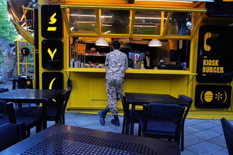 Un soldado de la Guardia Revolucionaria se ve en el mostrador de un restaurante de comida rápida en el norte de Teherán, Irán, el domingo 10 de mayo de 2026. (AP Foto/Vahid Salemi)