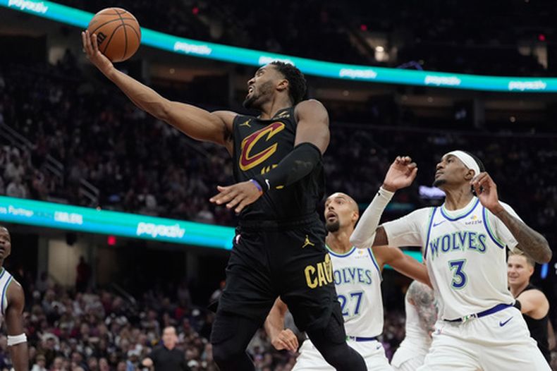 El base de los Cavaliers de Cleveland Donovan Mitchell salta hacia la canasta frente a Rudy Gobert y Jaden McDaniels de los Timberwolves de Minnesota el lunes 26 de octubre del 2026. (AP Foto/Sue Ogrocki.