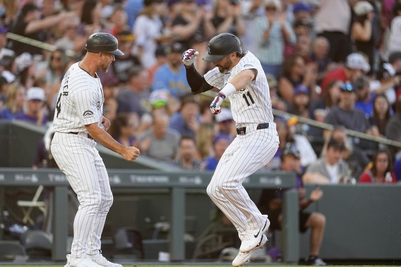 Warren Schaeffer (izquierda), coach de la antesala de los Rockies de Colorado felicita a Jake Cave, quien conectó un jonrón ante los Cerveceros de Milwaukee el jueves 4 de julio de 2024 (AP Foto/David Zalubowski)