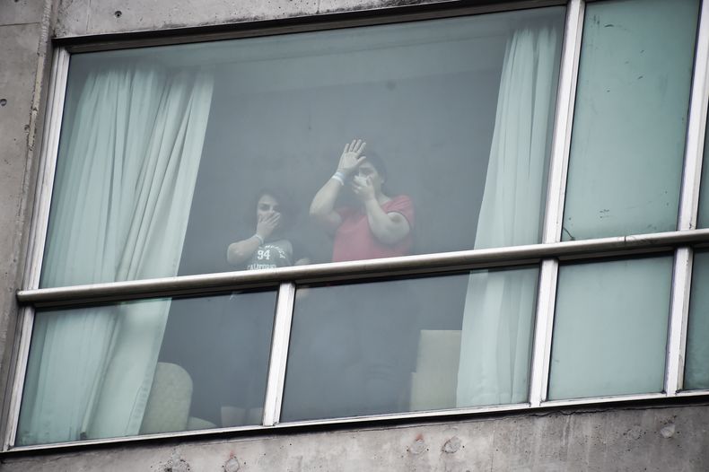 Migrantes deportados por Estados Unidos saludan a la prensa desde el interior de un hotel, el miércoles 19 de febrero de 2025, en Ciudad de Panamá. (AP Foto/Agustín Herrera)
