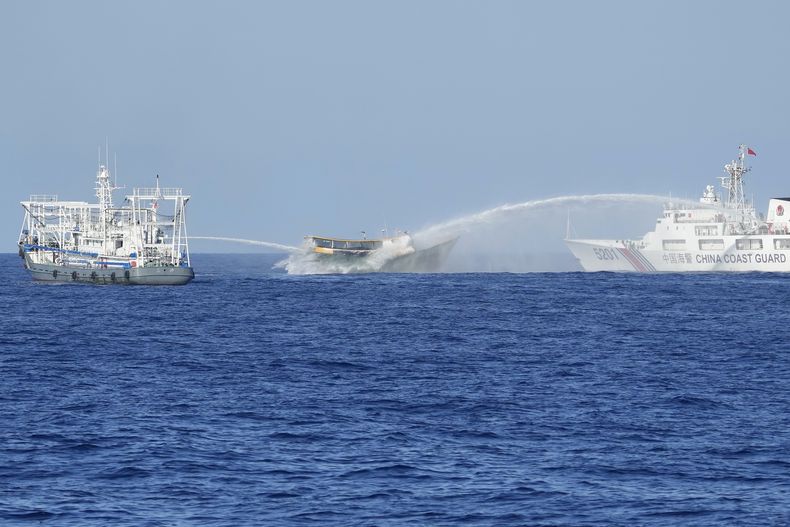 ARCHIVO - El barco filipino de abastecimiento Unaizah May 4, en el centro, es alcanzado por cañones de agua de dos barcos guardacostas chinos cuando intentaba llegar al disputado atolón Second Thomas, en el Mar de China Meridional. (AP Foto/Aaron Favila, Archvo)