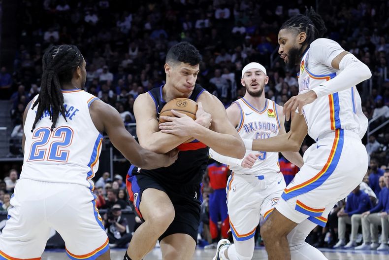 El alero de los Pistons de Detroit Simone Fontecchio, segundo desde la izquierda, conduce hacia la canasta contra los escoltas del Thunder de Oklahoma City Cason Wallace (22) e Isaiah Joe, a la derecha, durante la primera mitad de un partido de baloncesto de la NBA el sábado 15 de marzo de 2025, en Detroit. (AP Foto/Duane Burleson)
