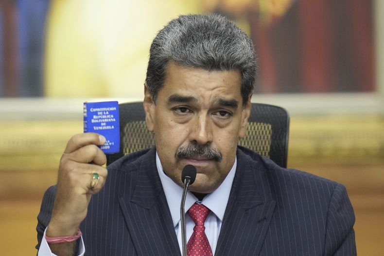 El presidente Nicolás Maduro sostiene una pequeña copia de la constitución, mientras ofrece una conferencia de prensa en el palacio presidencial de Miraflores, en Caracas, Venezuela, el miércoles 31 de julio de 2024. (AP Foto/Matías Delacroix)