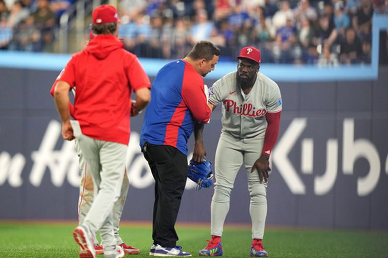 El cubano Adolis García de los Filis de Filadelfia recibe tratamiento antes de ser auxiliado para salir en la séptima entrada ante los Azulejos de Toronto el miércoles 10 de junio del 2026. (Chris Young/The Canadian Press via AP)