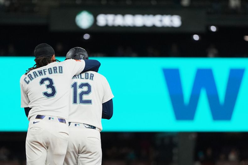 J.P. Crawford (3), de los Marineros de Seattle, abraza a su compañero Josh Naylor (12) después de que Naylor bateara un sencillo de oro para dejar tendidos en el terreno a los Astros de Houston en 10 entradas, el miércoles 23 de septiembre de 2026, en Seattle. (AP Foto/Lindsey Wasson)