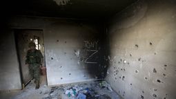 ARCHIVO - Un soldado ingresa a una casa acribillada a balazos cubierta por las iniciales del Cartel del Golfo (CDG) y Los Zetas (Z) en Ciudad Victoria, estado de Tamaulipas, México, el 6 de septiembre de 2014. (AP Foto/Eduardo Verdugo, Archivo)