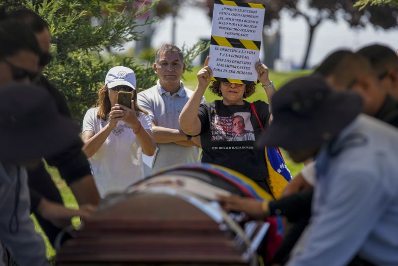 Una persona muestra un letrero de protesta durante el entierro del exteniente venezolano Ronald Ojeda en el cementerio Canaan en Santiago, Chile, el viernes 8 de marzo de 2024. De acuerdo con el fiscal Héctor Barros, Ojeda fue secuestrado el 21 de febrero y encontrado muerto enterrado a las afueras de la capital el 1 de marzo. (AP Foto/Esteban Félix)