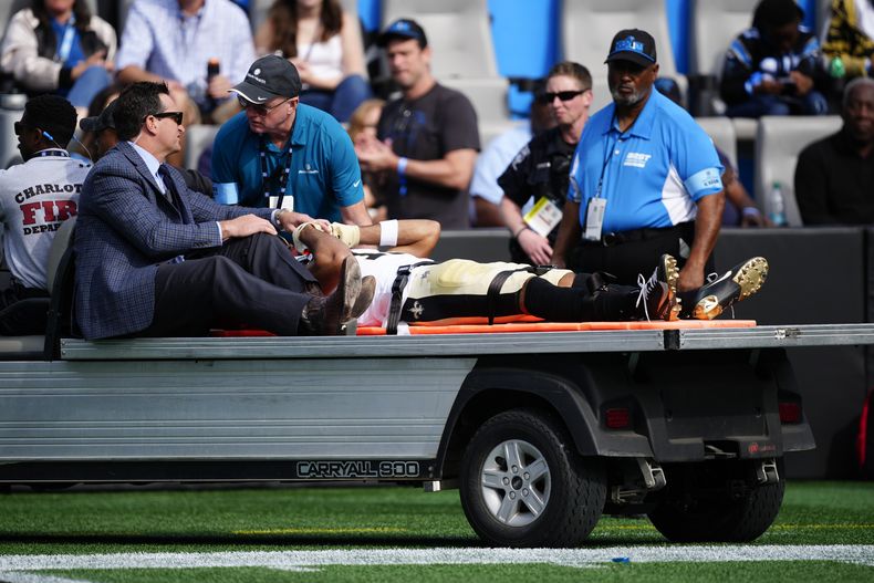 Chris Olave, wide receiver de Saints, es retirado del campo en un carrito después de resultar con una conmoción durante la primera mitad del partido de la NFL en contra de los Panthers de Carolina, el domingo 3 de noviembre de 2024, en Charlotte, Carolina del Norte. (AP Foto/Jacob Kupferman)
