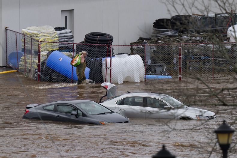 Un hombre camina cerca de unos vehículos abandonados en el estacionamiento inundado de un centro comercial tras los fuertes aguaceros en Halifax, Nueva Escocia, Canadá, el sábado 22 de julio de 2023. (Darren Calabrese/The Canadian Press vía AP)
