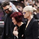 La familia de Ozzy Osbourne, de izquierda a derecha, Jack Osbourne, Sharon Osbourne y Kelly Osbourne, depositan flores y ven las flores colocadas en el banco del puente Black Sabbath en Broad Street en memoria del líder de Black Sabbath, Ozzy Osbourne, antes de la procesión fúnebre, en Birmingham, Inglaterra, el miércoles 30 de julio de 2025. (Jacob King/PA via AP)