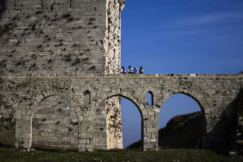 Varas mujeres permanecen sobre un puente en el sitio arqueológico de Crac des Chevaliers, el domingo 26 de enero de 2025, en las afueras de Homs, Siria. (AP Foto/Khalil Hamra)