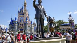 Visitantes del parque temático Magic Kingdom caminan cerca de una estatua de Walt Disney y Mickey Mouse, el viernes 14 de julio de 2023, en Lake Buena Vista, Florida. (AP Foto/John Raoux)