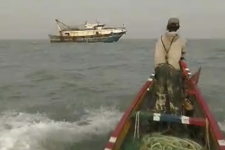 En la imagen, tomada de un video proporcionado por el pescador Salif Ndure, él y un colega, derecha, se acercan a un barco de pesca industrial que, afirman, pescaba dentro del radio de 9 millas náuticas de los botes de pesca artesanal frente a la costa de Gambia, el 3 de diciembre de 2024. (Salif Ndure vía AP)