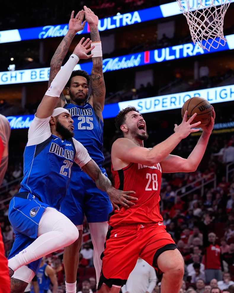Alperen Sengun (28), de los Rockets de Houston, tira ante la presión defensiva de Daniel Gafford (21) y P.J. Washington (25), de los Mavericks de Dallas, durante la segunda mitad del juego de baloncesto de la NBA, el lunes 3 de noviembre de 2025, en Houston. (AP Foto/Ashley Landis)