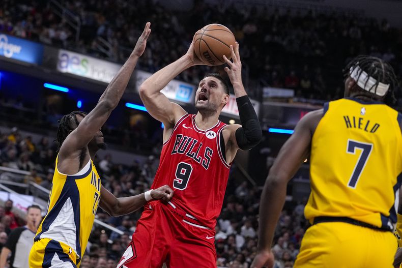 Nikola Vucevic (9), de los Bulls de Chicago, ataca el aro entre los defensivos de los Pacers de Indiana Aaron Nesmith (23) y Buddy Hield (7) durante la segunda mitad del juego de baloncesto de la NBA, el lunes 30 de octubre de 2023. Los Bulls vencieron a los Pacers 112-105. (AP Foto/Michael Conroy)