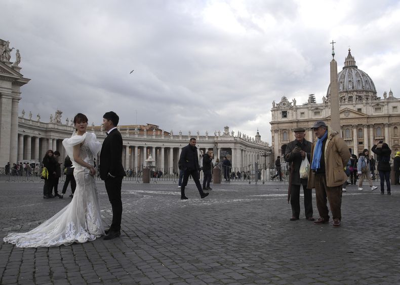 ARCHIVO - La gente observa a una pareja china, vestida de boda, mientras posa para unas fotos frente a la Plaza de San Pedro, en el Vaticano, el 17 de enero de 2019. (AP Foto/Alessandra Tarantino, archivo)