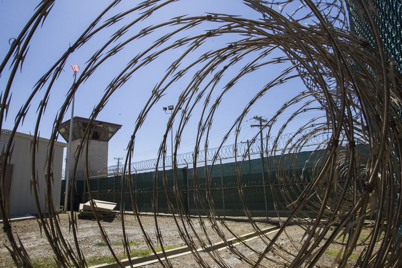 ARCHIVO - En esta fotografía del 17 de abril de 2019 revisada por oficiales militares de Estados Unidos se muestra una torre de control a través de alambre de púas dentro de un centro de detención en la base naval de la Bahía de Guantánamo, en Cuba. (AP Foto/Alex Brandon, Archivo)