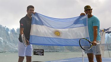 americateve | En esta fotograf&iacute;a distribuida por el Ministerio de Turismo de Argentina, el tenista espa&ntilde;ol Rafael Nadal (derecha) y el serbio Novak Djokovic sostienen una bandera argentina mientras posan frente al glaciar Perito Moreno desde una cancha de