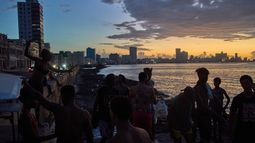 La gente observa la puesta de sol desde el Malecón durante un apagón en La Habana, el lunes 16 de marzo de 2026. (Foto AP/Ramón Espinosa)