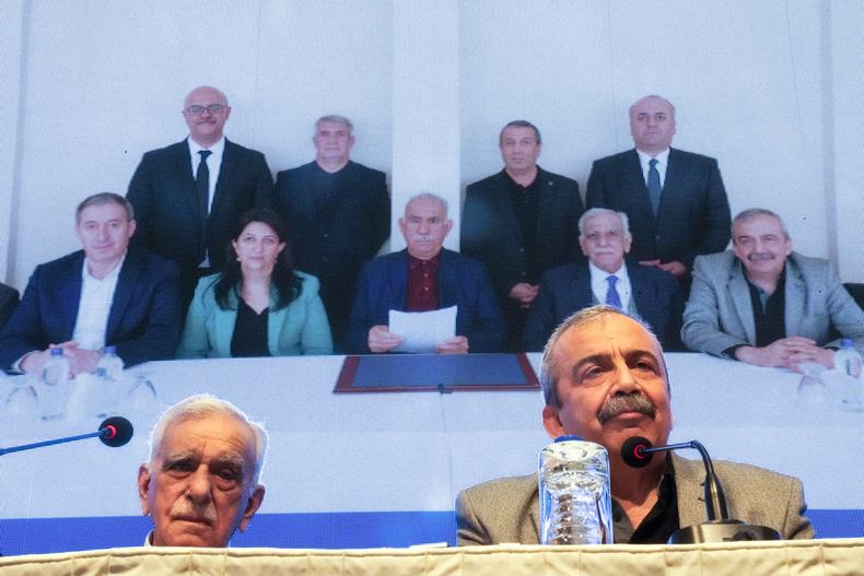 ARCHIVO - Miembros de la delegación pro-kurda del Partido del Pueblo Igualdad y Democracia, o DEM, publican una declaración del líder encarcelado del rebelde Partido de los Trabajadores del Kurdistán, o PKK, Abdullah Ocalan, en el centro en la foto de fondo, en Estambul, Turquía, jueves 27 de febrero de 2025. (AP foto/Khalil Hamra, archivo)