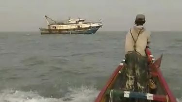 En la imagen, tomada de un video proporcionado por el pescador Salif Ndure, él y un colega, derecha, se acercan a un barco de pesca industrial que, afirman, pescaba dentro del radio de 9 millas náuticas de los botes de pesca artesanal frente a la costa de Gambia, el 3 de diciembre de 2024. (Salif Ndure vía AP)
