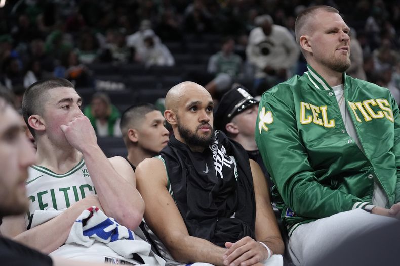El armador de los Celtics de Boston, Payton Pritchard (izquierda), el base Derrick White (centro), y el pívot Kristaps Porzingis (derecha), observan desde el banquillo mientras los Cavaliers de Cleveland lideran sobre los Celtics de Boston durante la segunda mitad del Juego 2 del baloncesto de la NBA, en la segunda ronda de la serie de postemporada, el jueves 9 de mayo de 2024, en Boston. (AP Foto/Steven Senne)