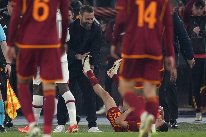 El técnico de la Roma Daniele De Rossi sonríe mientras estira las piernas Stephan El Shaarawy durante el partido de cuartos de final de la Liga Europa contra el AC Milan, el 18 de abril de 2024. (AP Foto/Andrew Medichini)