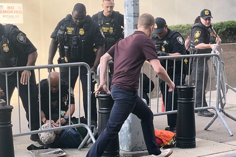 En esta imagen cortesía de Robert Sullivan se puede ver a varios agentes que rodean a una persona tendida en el piso cerca del lugar de un incendio en el 26 de Federal Plaza en el bajo Manhattan, el lunes 20 de julio de 2026, en Nueva York. (Robert Sullivan vía AP)