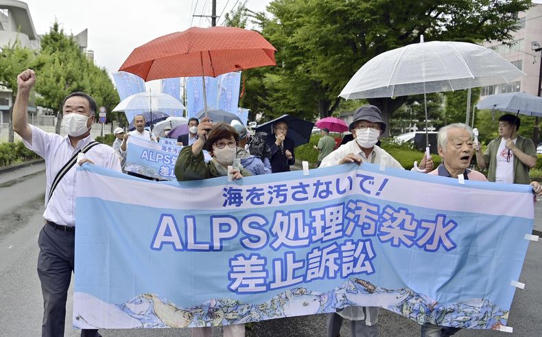 Demandantes y sus seguidores, que exigen la revocación del plan de descarga de agua de TEPCO, operador de la planta nuclear de Fukushima, marchan a la Corte Distrital de Fukushima para presentar una demanda, en Fukushima, noreste de Japón, viernes 8 de setiembre de 2023. (Kyodo News via AP)